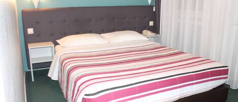 A hotel room with a bed, nightstands, a telephone, and a wall-mounted light fixture.