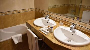 A bathroom with two sinks, a bathtub, and a mirror.