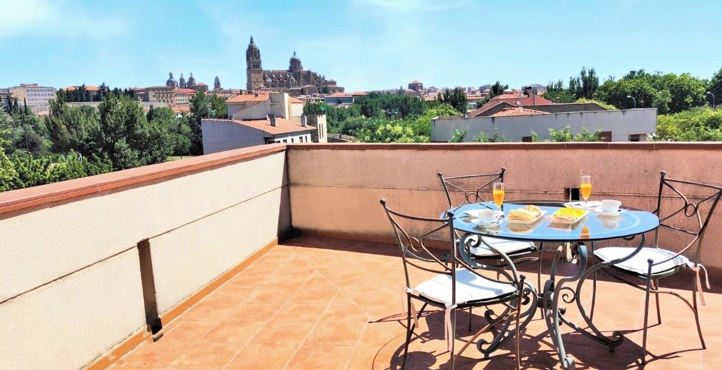 Een dak terras met een tafel voor twee, met uitzicht op een stadsgezicht met historische gebouwen.