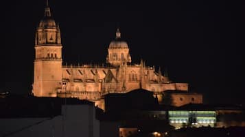 Uma catedral grande e iluminada, com duas torres imponentes e uma cúpula central, cercada por edifícios modernos.