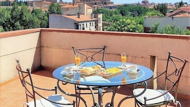 A round table with chairs on a terrace, overlooking a historic building with domes and towers. - Hotel Ele Puente Romano (Salamanca)