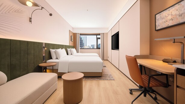A modern hotel room with a bed, a desk, a chair, a small table, and a wall-mounted TV. - Hilton Garden Inn Chengdu Tianfu Square Center (Chengdu)