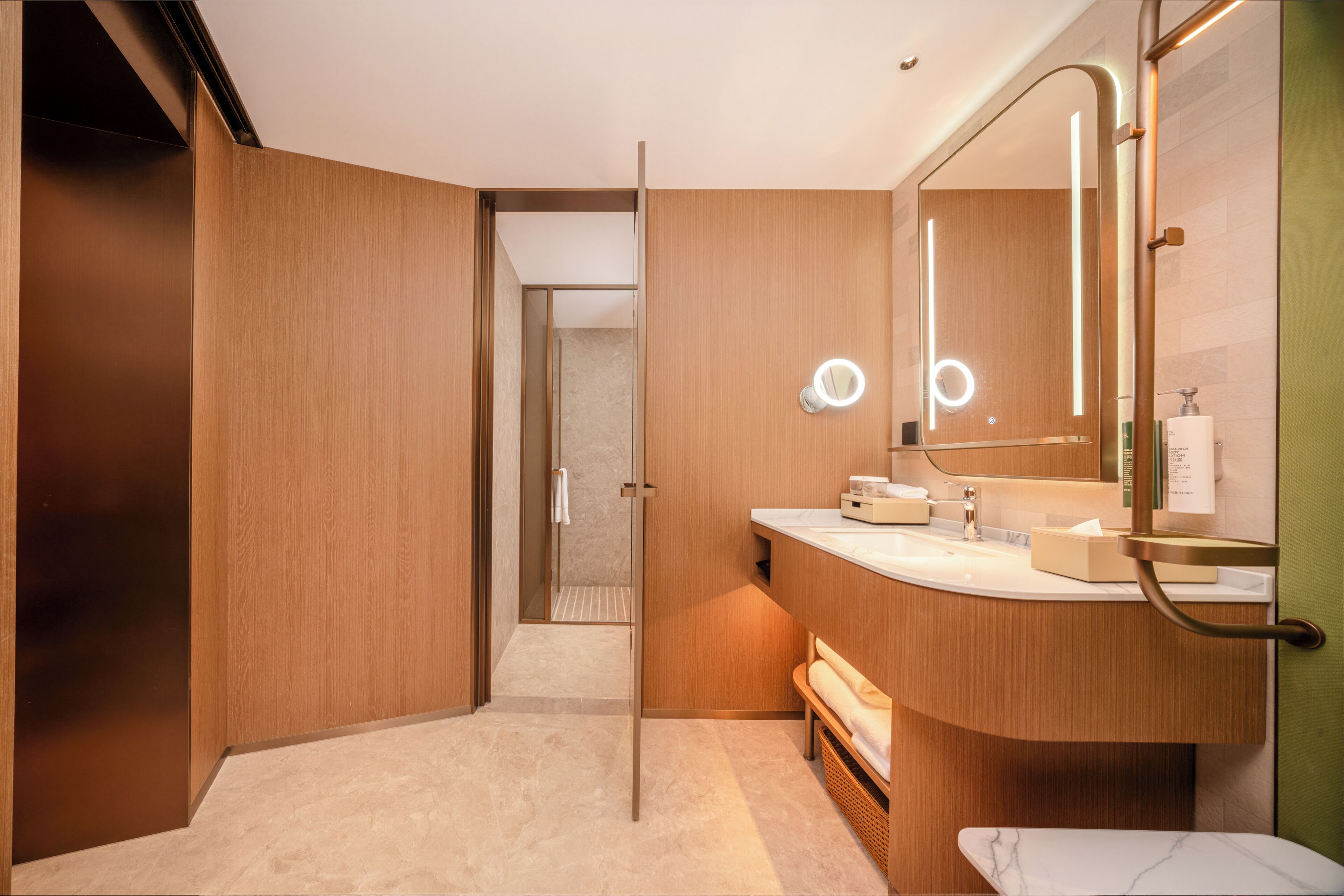 A modern bathroom with a wooden vanity, a large mirror, and a shower area.