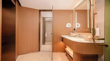 A modern bathroom with a wooden vanity, a large mirror, and a shower area.