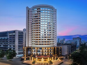 A high-rise hotel with multiple floors, a well-lit entrance, and a visible name sign.