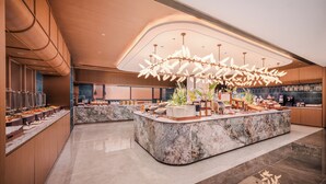 A modern hotel lobby with a marble reception desk, buffet area, and a large decorative chandelier. - Hilton Garden Inn Chengdu Tianfu Square Center (Chengdu)