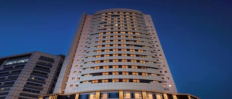 A modern hotel building with a curved facade, multiple floors, and illuminated windows.