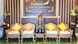 A reception area with a wooden reception desk, two sofas with yellow cushions, and a decorative shrine in the center.