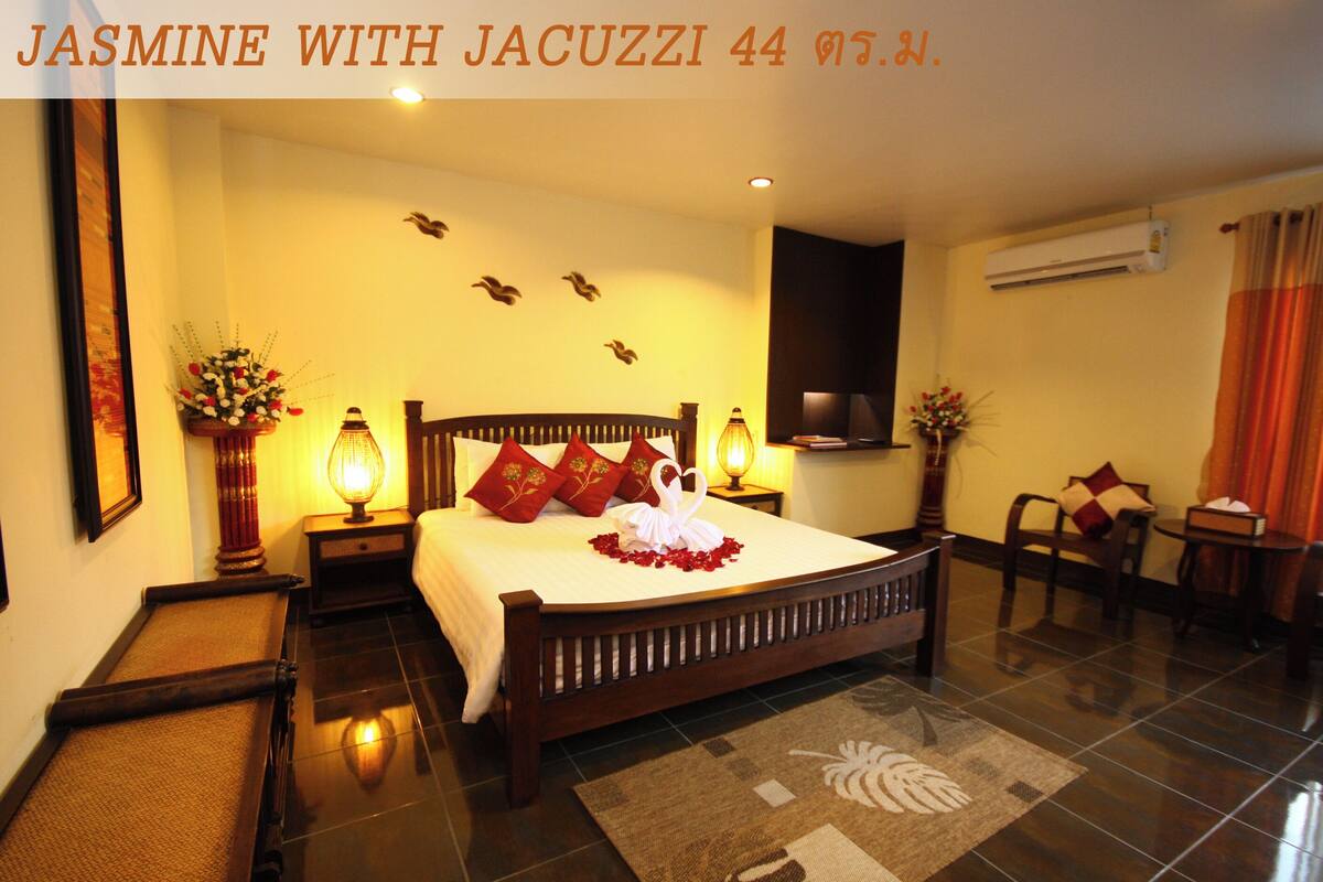 A neatly arranged hotel room with a large bed, a sitting area with a chair and table, and a wall-mounted TV.