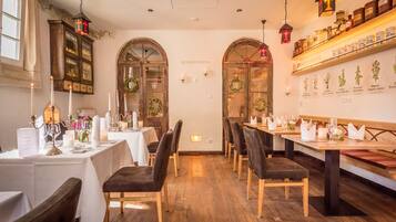 Un interior de restaurante con mesas de madera, sillas oscuras y un ambiente iluminado con velas.