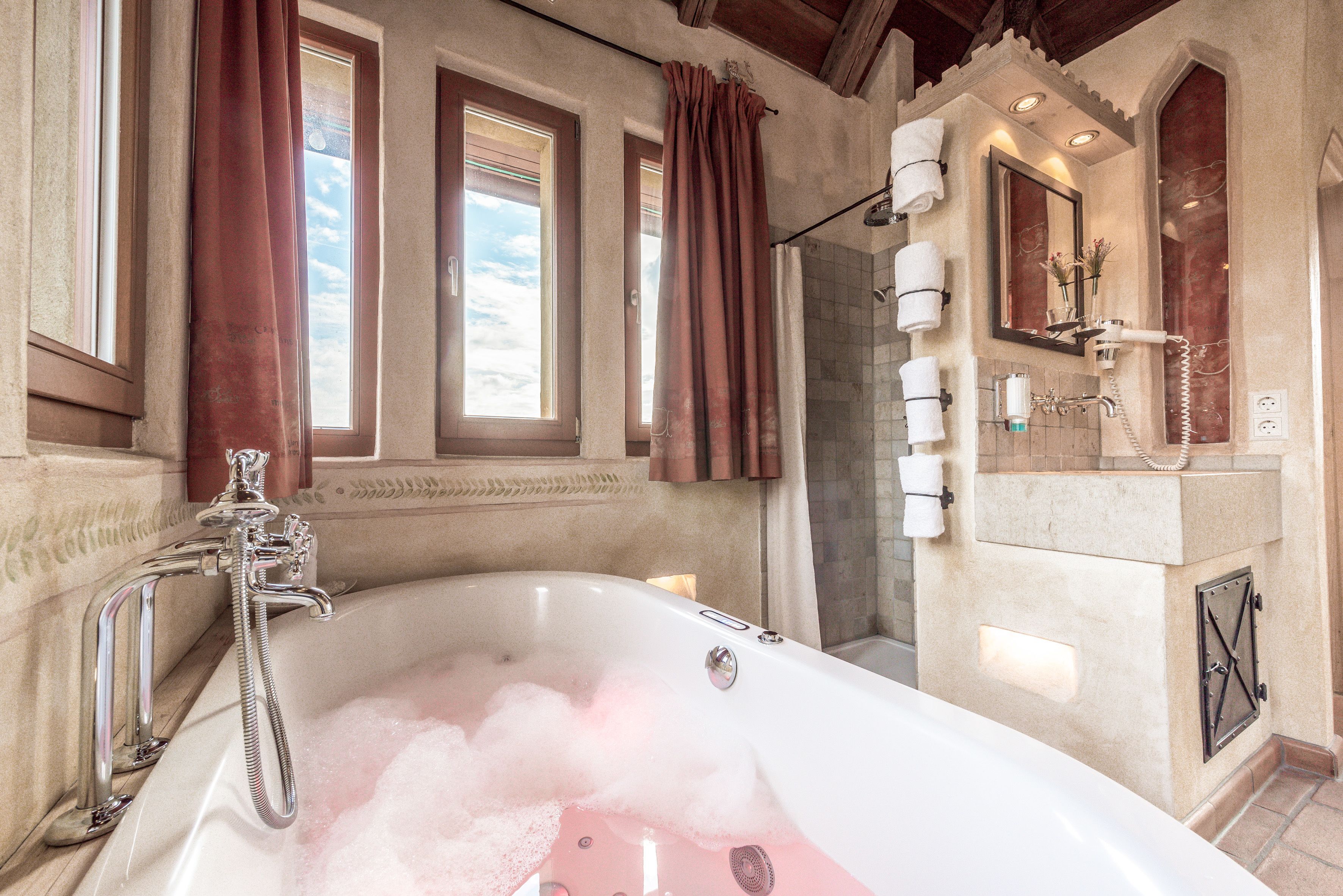A bathroom with a large bathtub, a shower, and a vanity with a mirror.