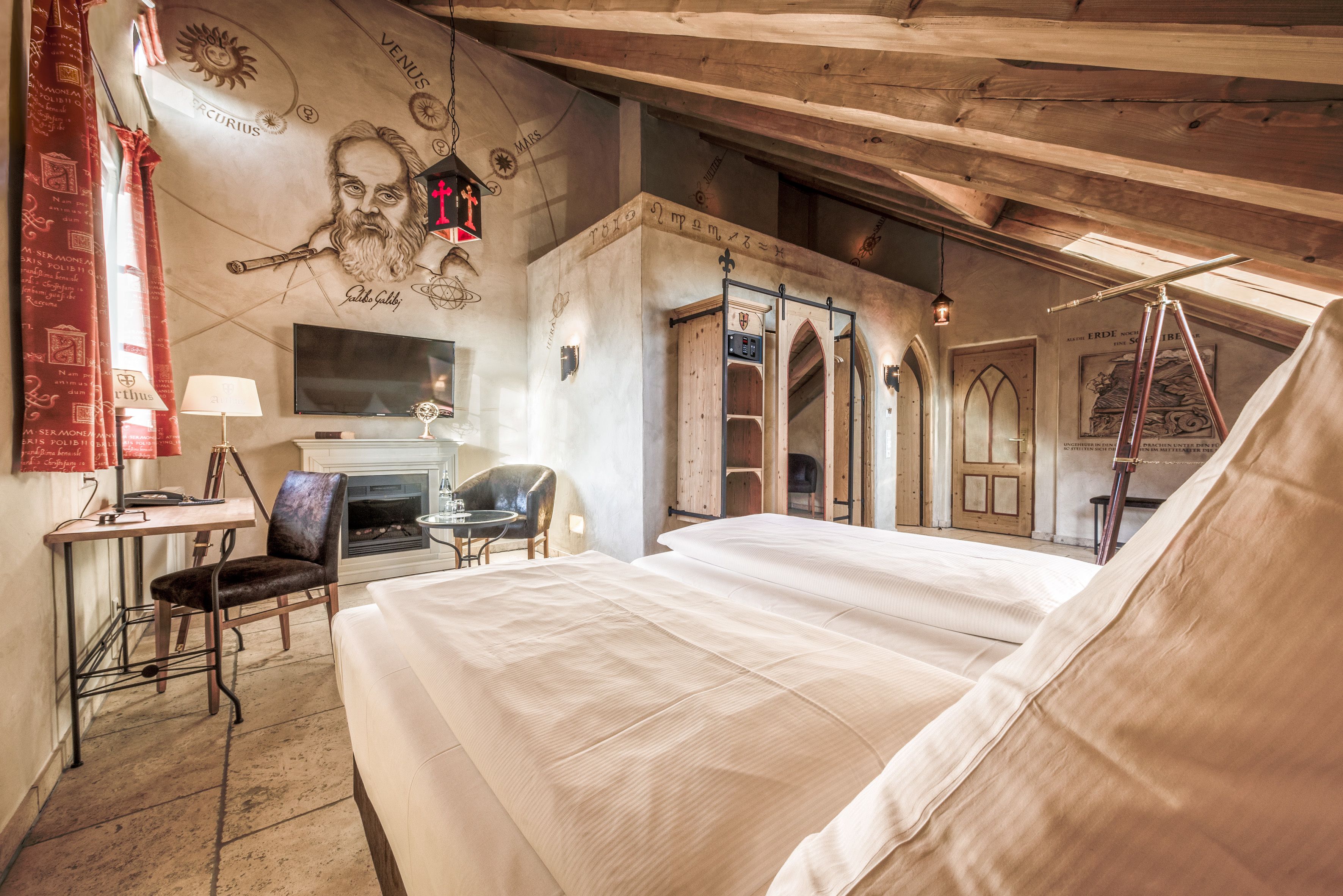 Una habitación con una cama grande, un escritorio con una silla, una chimenea y un mural en la pared.