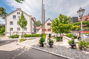 Un hôtel de style architectural européen traditionnel, doté d’une cour pavée, d’un espace d’accueil et d’un panneau indiquant l’emplacement du parking.