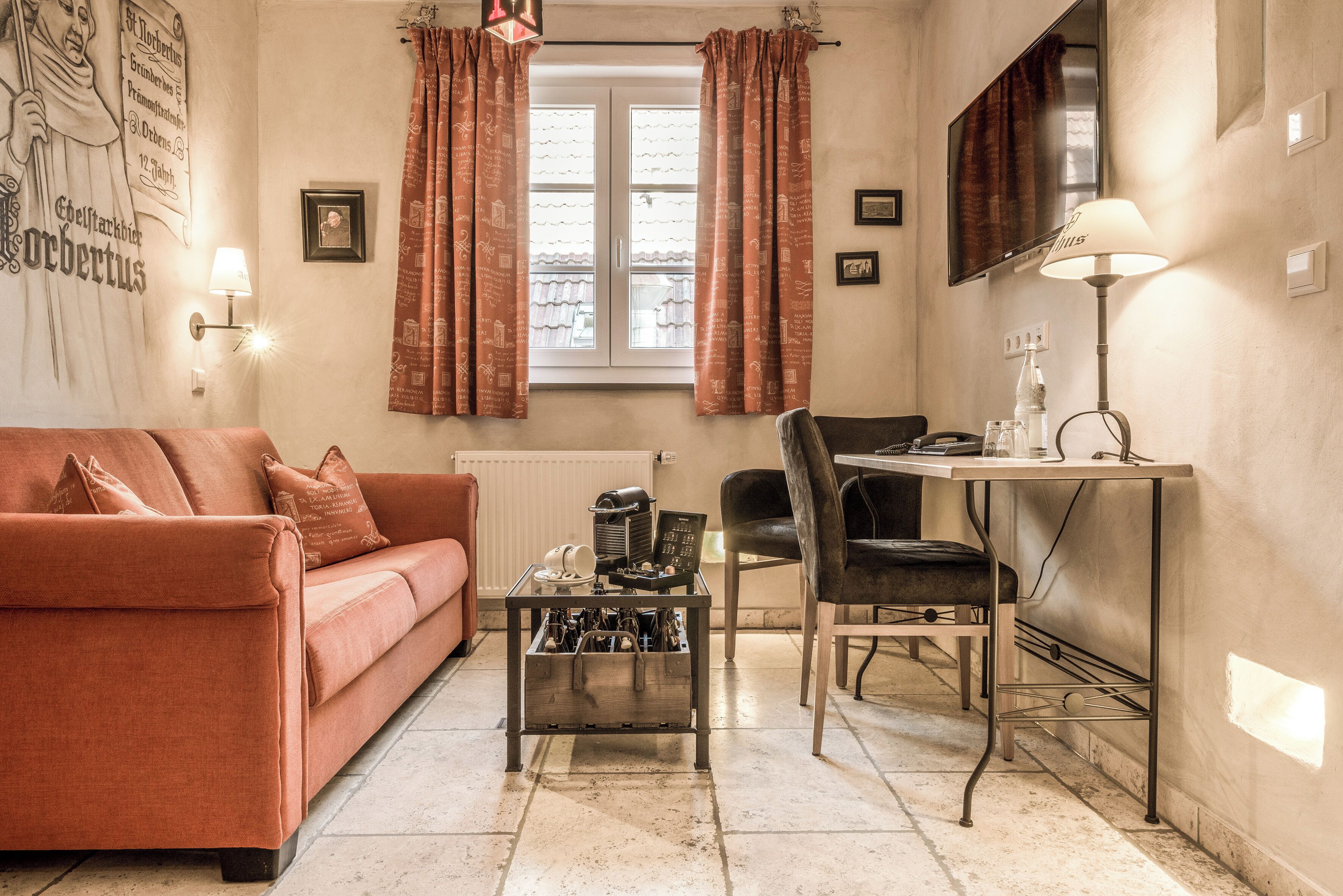 Una sala de estar acogedora con un sofá, una mesa de centro, un sillón y un televisor montado en la pared.