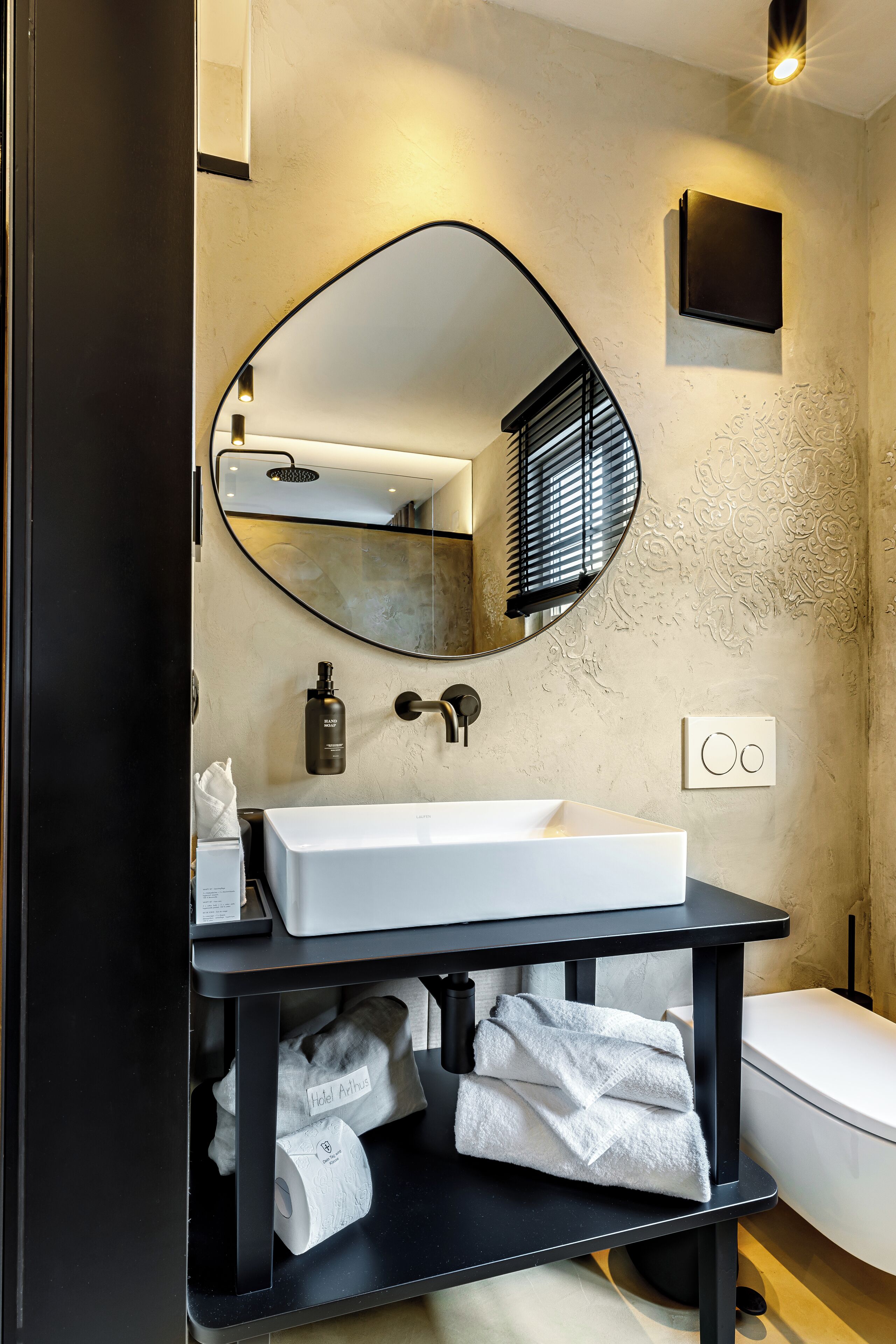 A modern bathroom with a white sink, a large mirror, and a black vanity.
