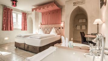 Una habitación de hotel con una cama doble, una bañera, un tocador con espejo y una ducha.