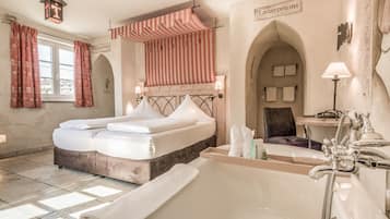 A hotel room with a large bed, a bathtub, and a shower. There are two towels on the bed and a towel on the floor.