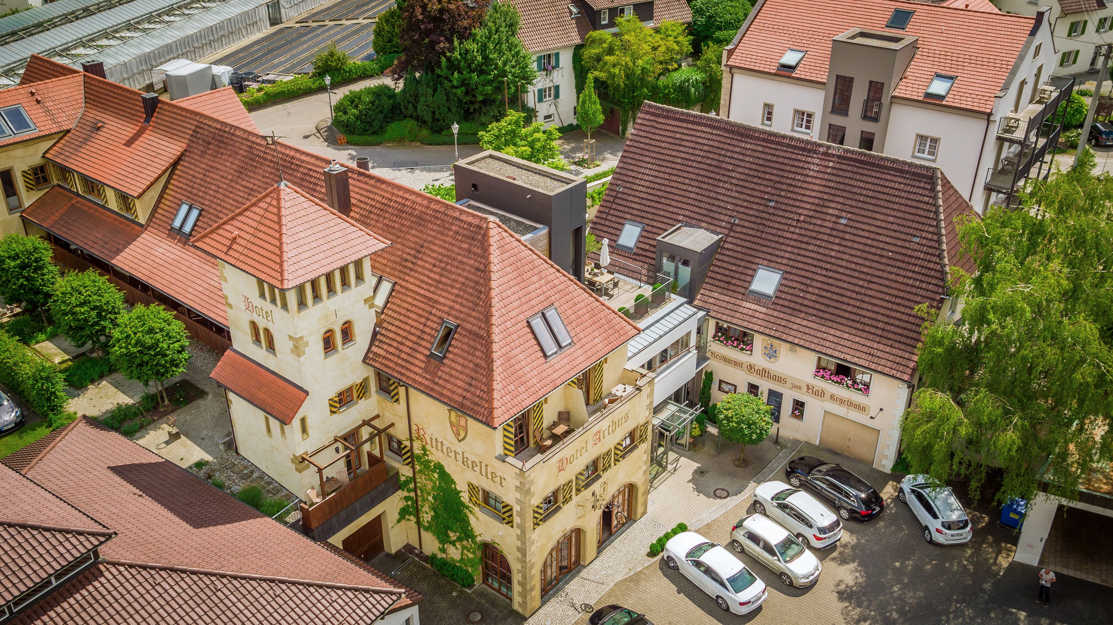 Ein Hotel im traditionellen europäischen Stil mit einem markanten Turm und einem Innenhof mit parkenden Autos.