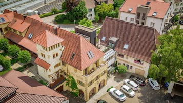 Ein Hotel im traditionellen europäischen Stil mit einem markanten Turm und einem Innenhof mit parkenden Autos.
