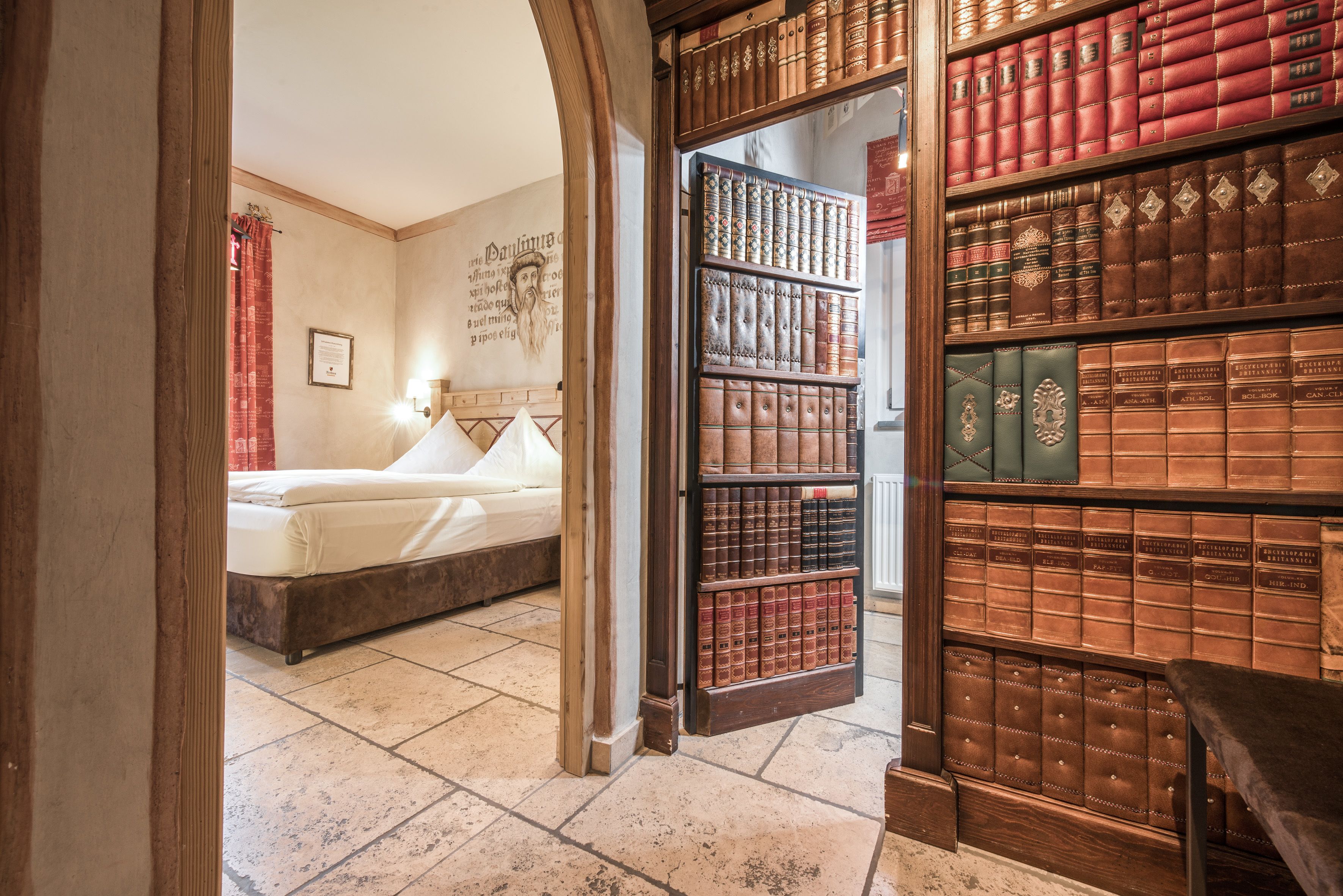 A room with a bed, a bookshelf filled with books, and a framed picture on the wall.