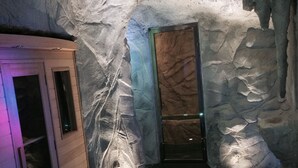 Quarto com parede de pedra, um armário de madeira e uma porta com superfície texturizada.