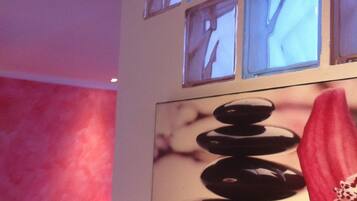 A wall with six square windows and a framed artwork of stacked stones and a flower.