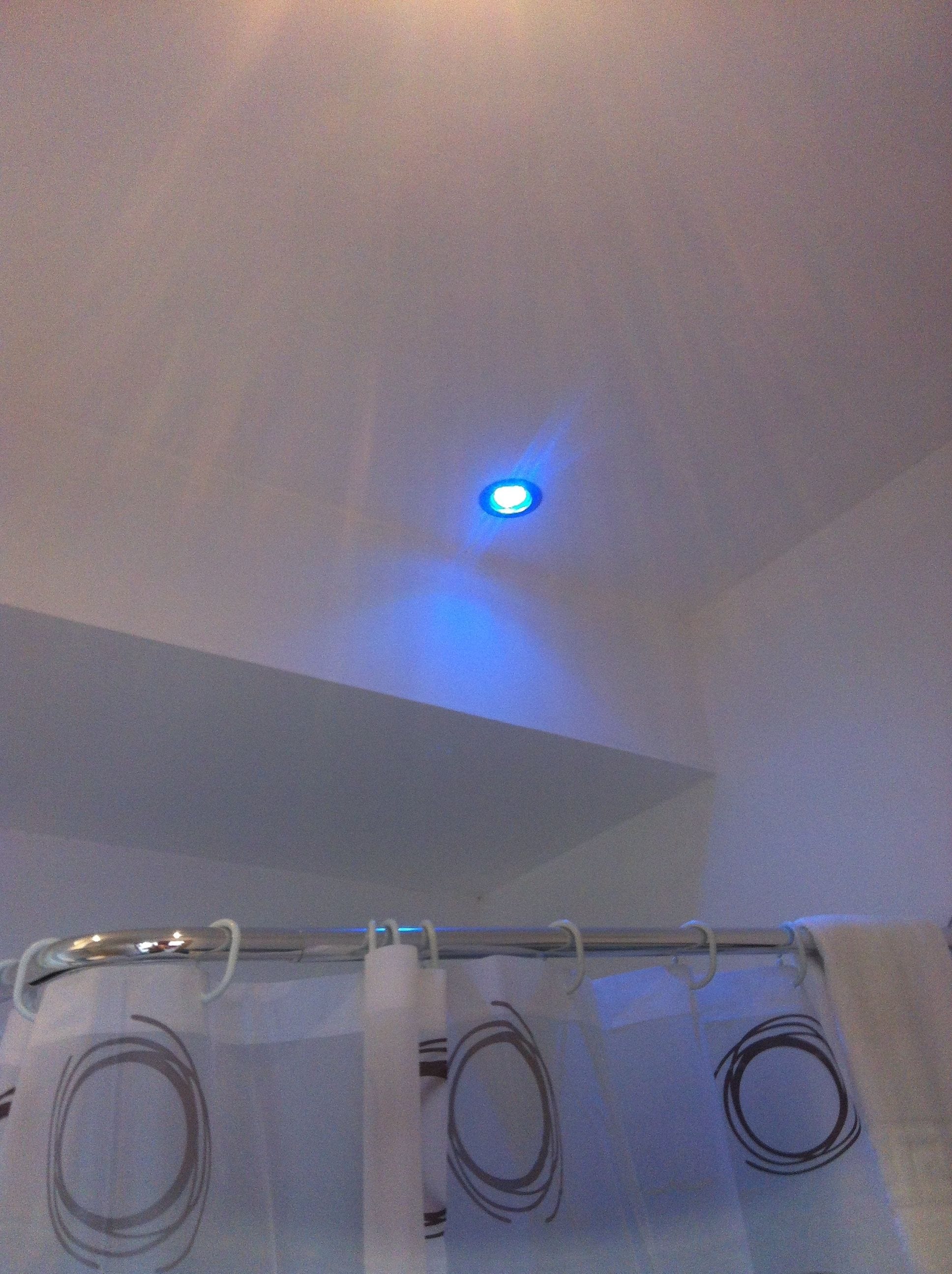 Un plafond avec un seul luminaire diffusant une lumière bleue.
