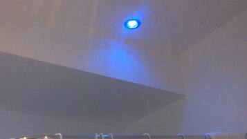 Un plafond avec un seul luminaire diffusant une lumière bleue.