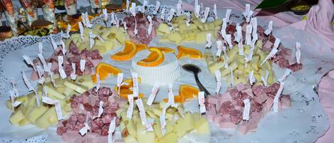 A large platter of assorted cheeses, meats, and fruits on a lace doily.