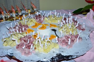Un grande piatto con formaggi misti, salumi e frutta su un sottotavolo di pizzo.