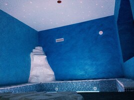 Una camera blu con una vasca da bagno bianca, una piccola finestra e un pavimento piastrellato.