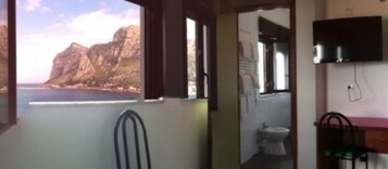 Una stanza con vista sulle scogliere e sul mare, un bagno e un lavandino.