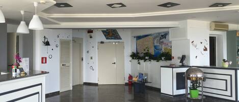 Un vestíbulo de hotel con una recepción, un mapa en la pared y un suelo limpio y pulido.