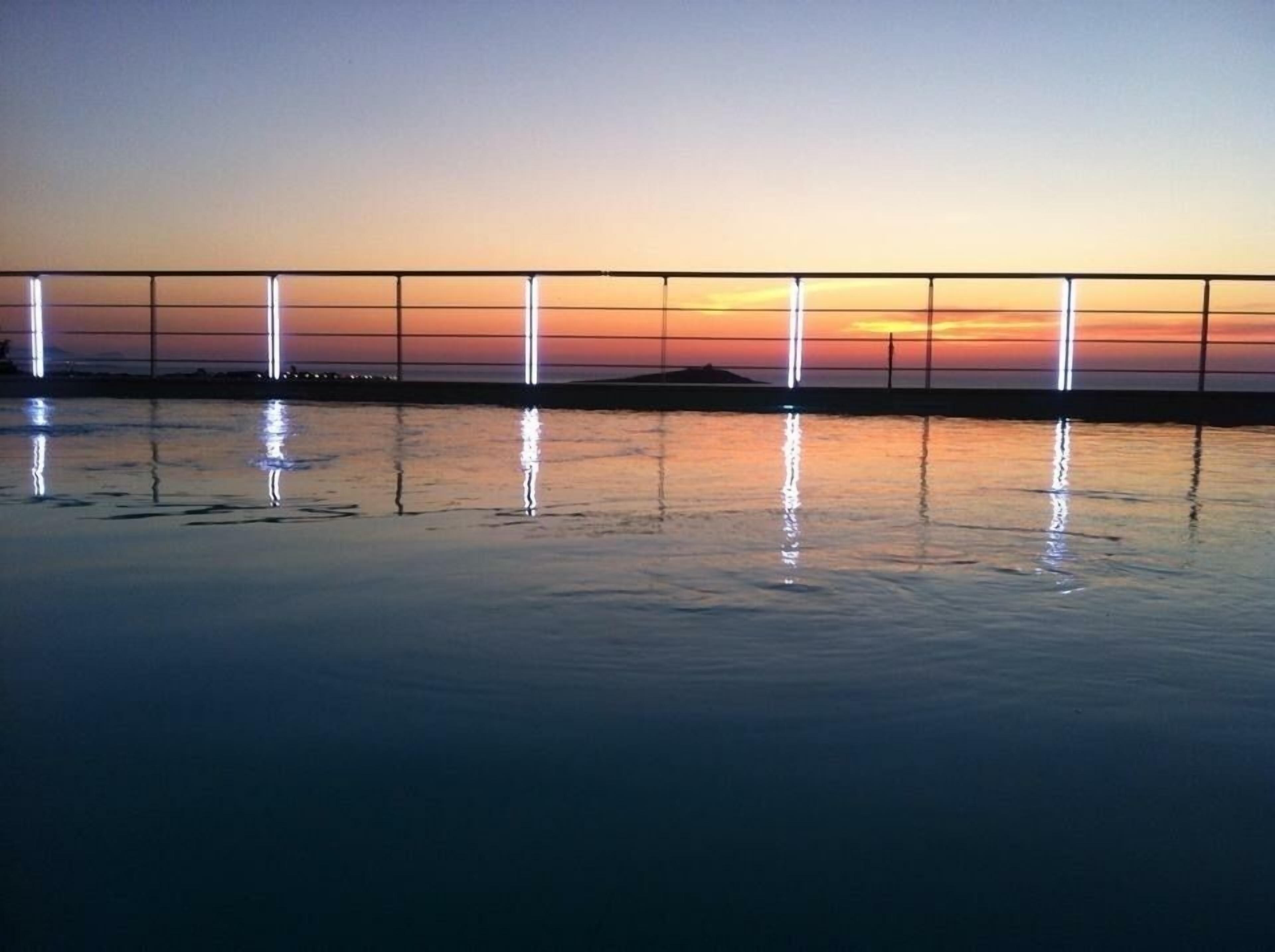 A bridge at sunset with lights reflecting on the water.