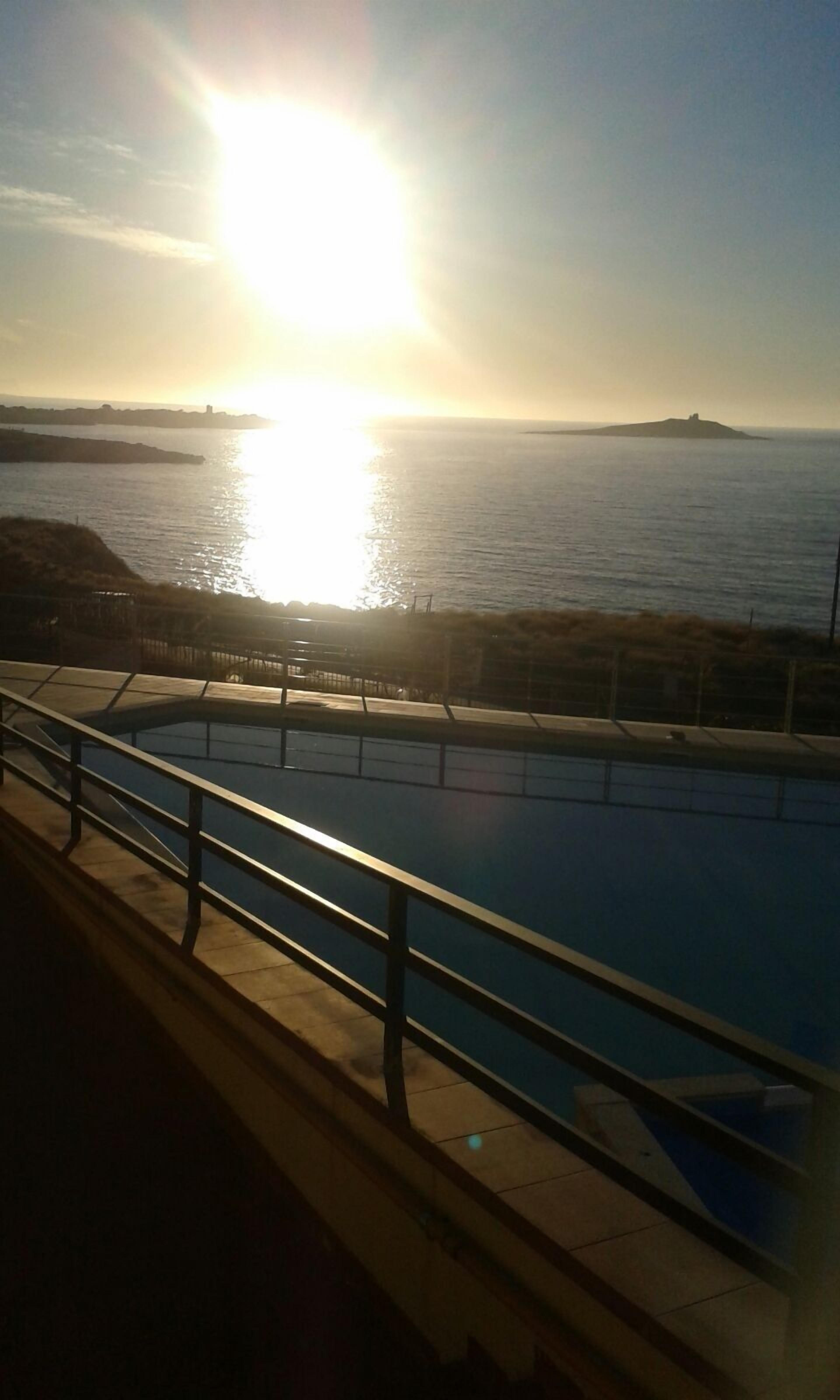 A swimming pool with a view of the sea and a distant island.