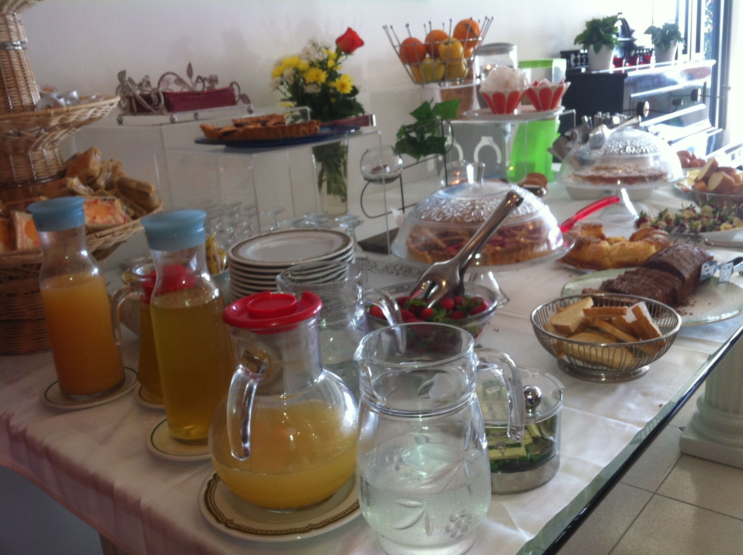 A buffet table with various food items, beverages, and condiments.