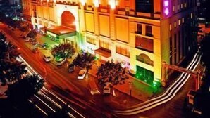 A multi-story hotel with a prominent arched entrance and a series of balconies.