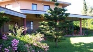 A two-story house with a covered porch, a lawn, and a small tree. - Bellavista Country House (Pescara)