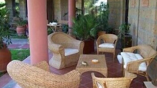 A covered outdoor seating area with wicker furniture and potted plants. - Bellavista Country House (Pescara)
