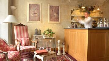 A bar area with a wooden counter, shelves with bottles and glasses, and a decorative chair with a striped cushion.