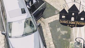 Een zwarte auto geparkeerd voor een gebouw met een bord waarop 'hotel Saint Pierre' staat.