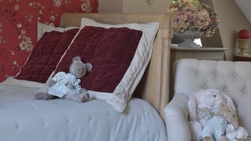 Een slaapkamer met een bed, een stoel, een lamp en een tafel met boeken en decoratieve spullen.