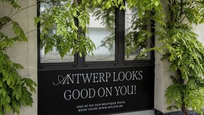 A building facade with a black sign that reads 'ANTWERP LOOKS GOOD ON YOU!' and a website address. - A Place - Boutique Hotel Emile (Antwerp)