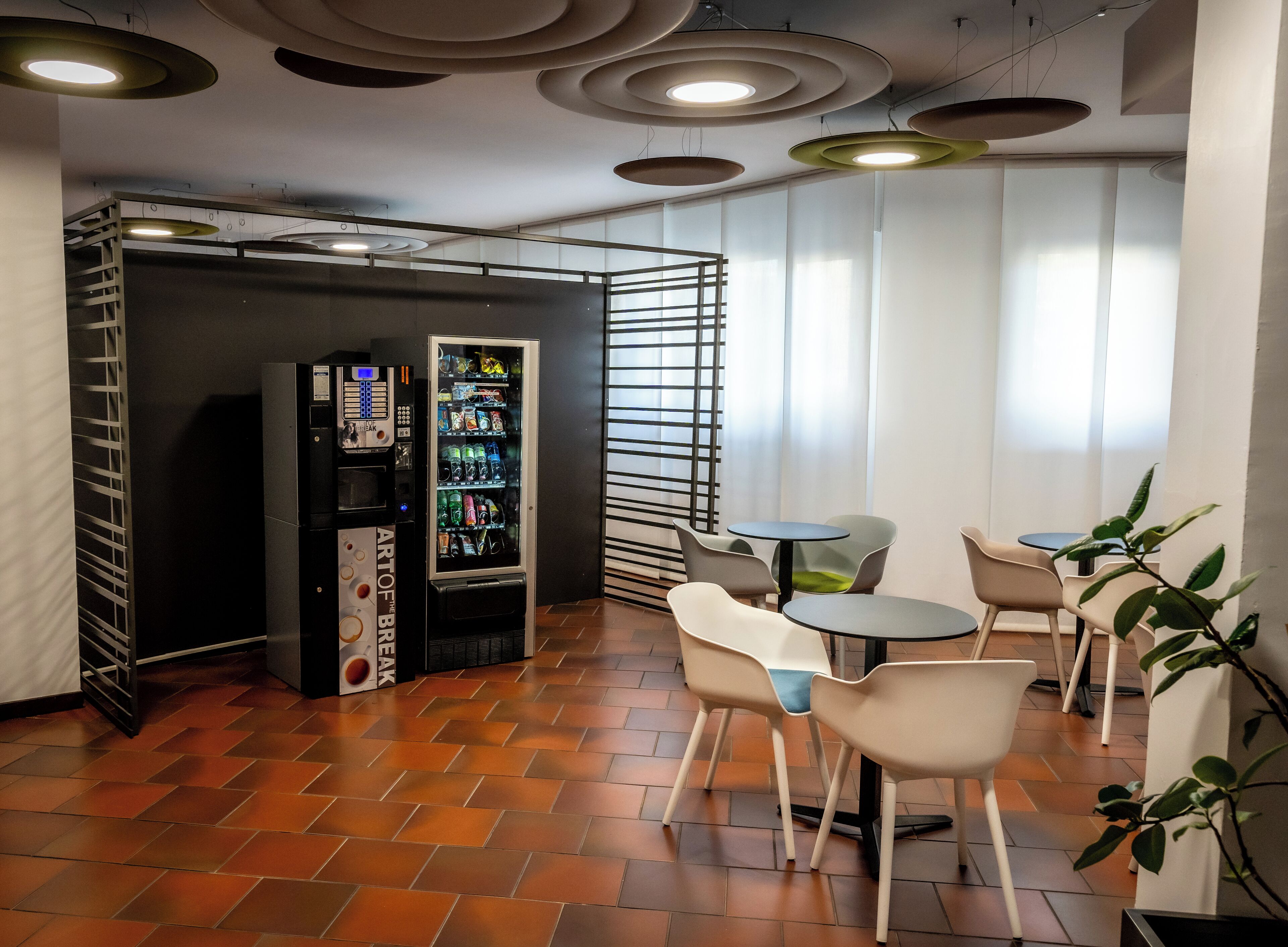 Ein moderner Aufenthaltsraum mit Automaten, Sitzgelegenheiten und einer dekorativen Decke.