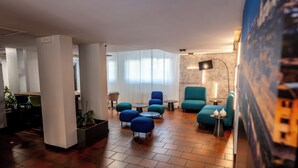 A modern lounge area with blue upholstered chairs, a coffee table, and a potted plant. -  Residence Porta al Prato (Florence)