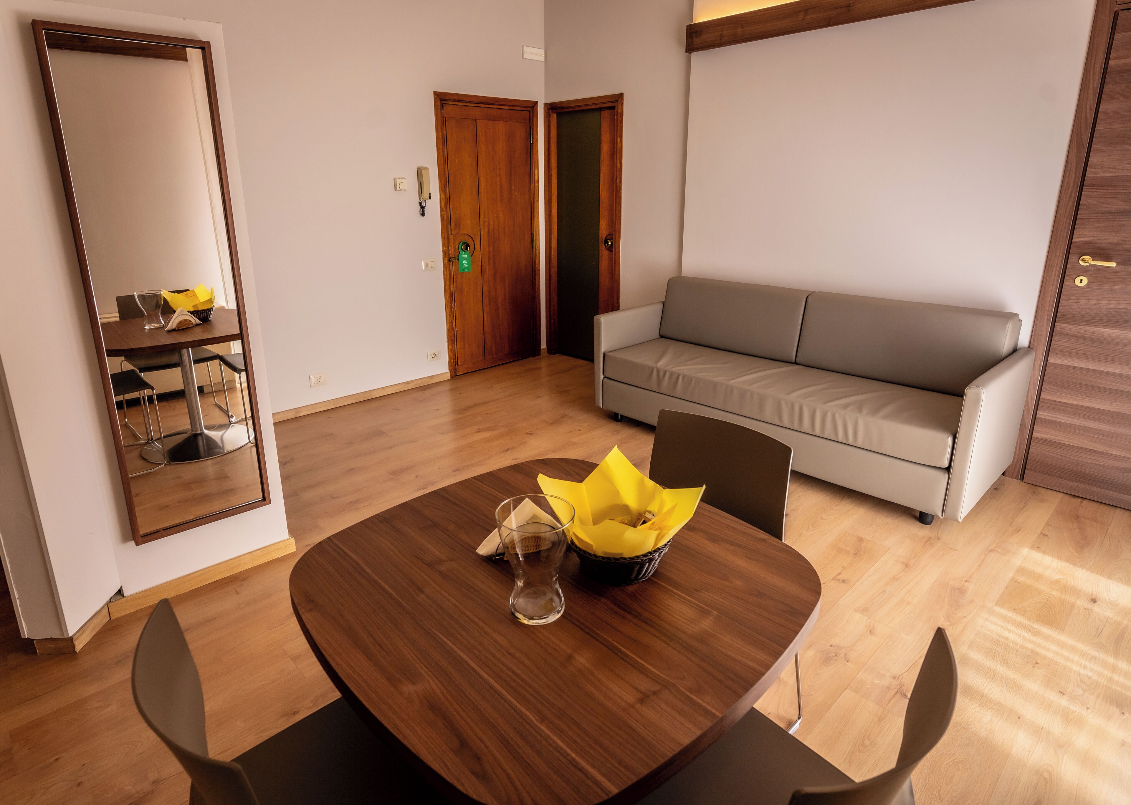 Quarto moderno com uma mesa de jantar de madeira, um sofá e um espelho.
