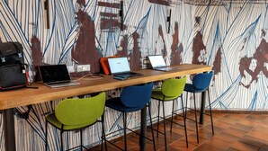 A modern workspace with a long wooden table, multiple laptops, and colorful chairs. -  Residence Porta al Prato (Florence)