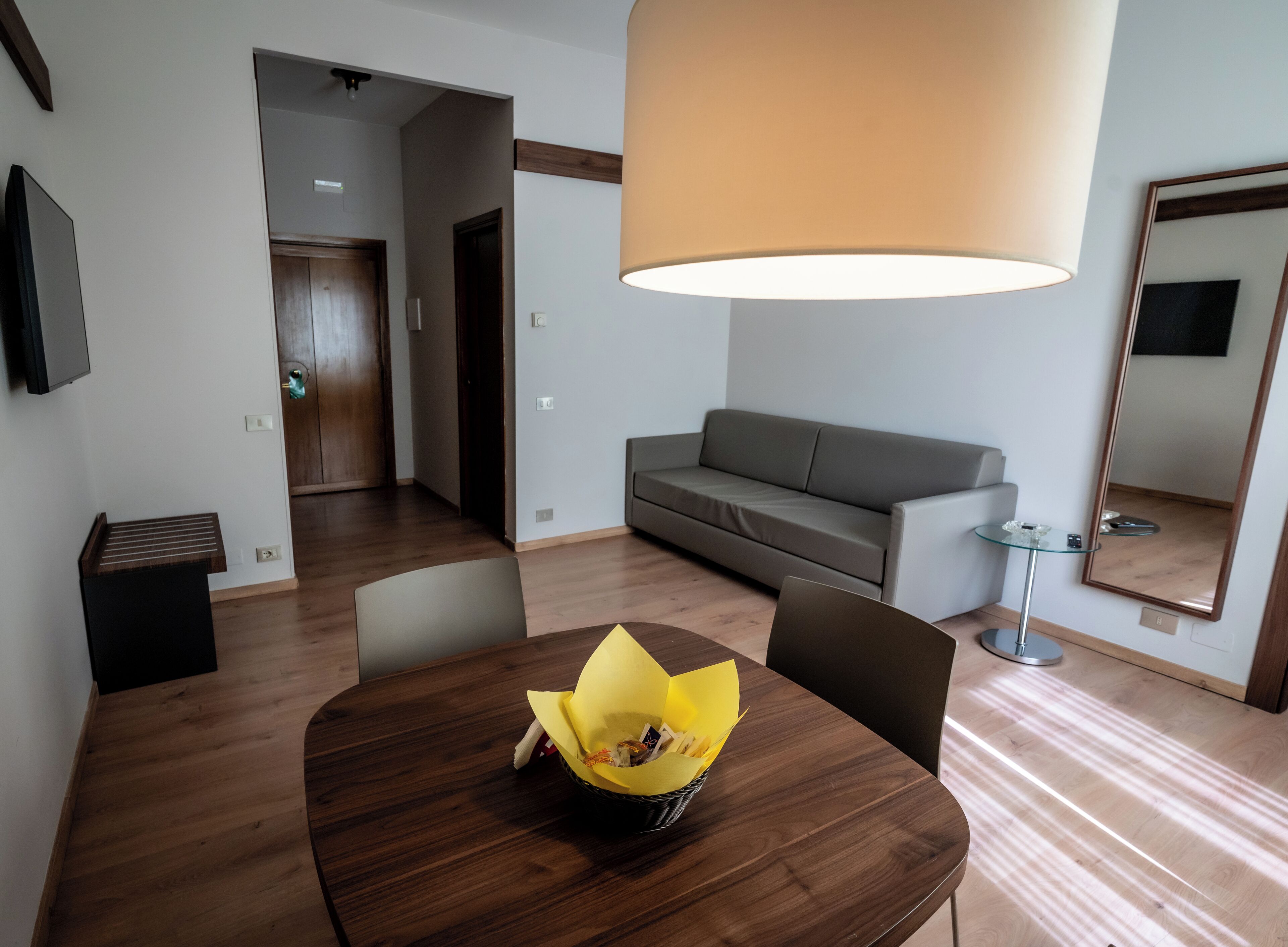 Un salon moderne avec une table à manger en bois, un canapé et un grand lampadaire.