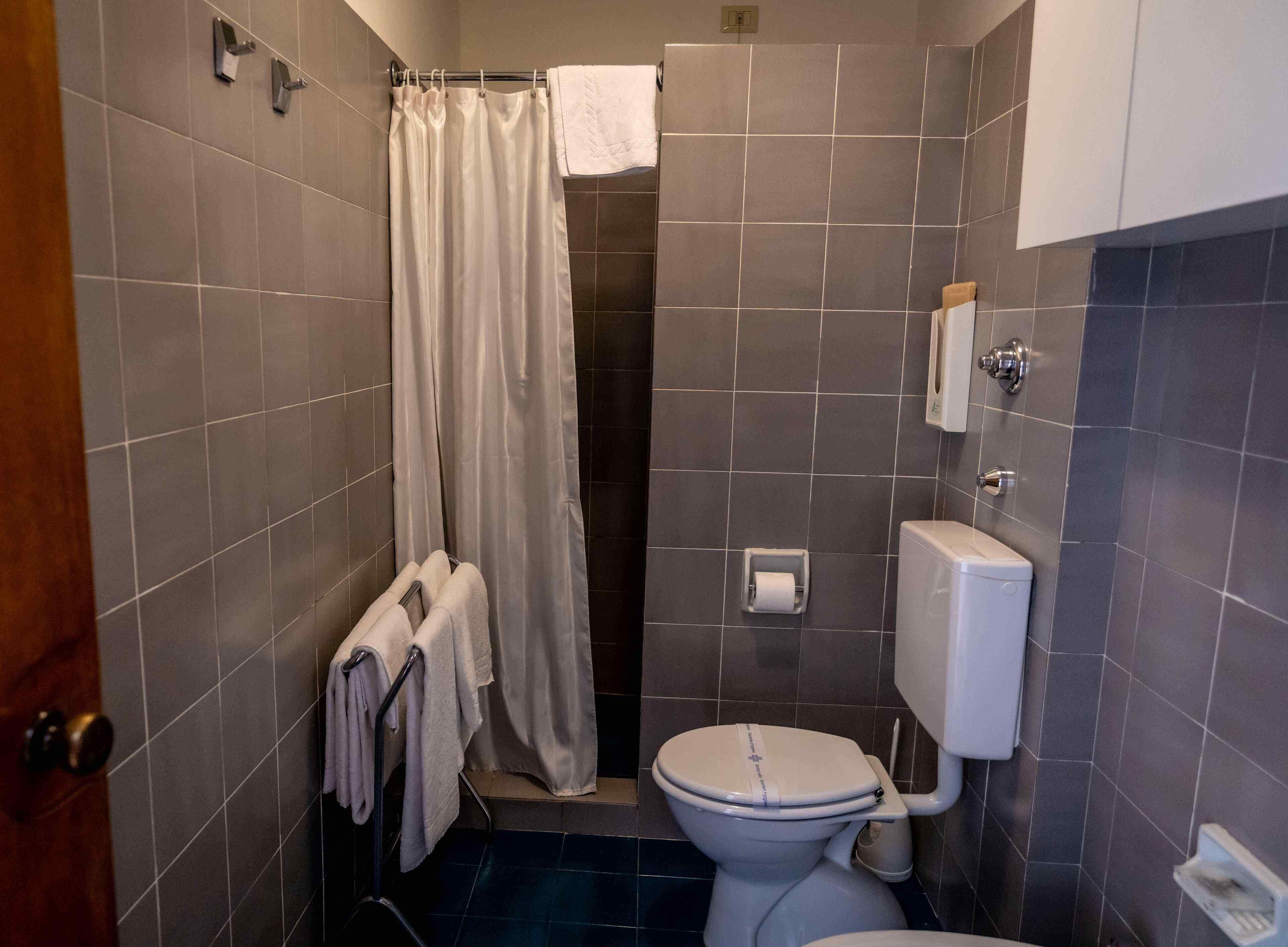 Ein kleines Badezimmer mit Toilette, einer Duschvorhang und einem Handtuchhalter.