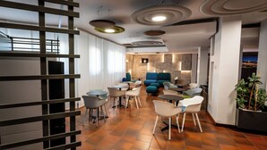 A modern lounge area with a mix of seating options, including chairs and sofas, arranged around tables. -  Residence Porta al Prato (Florence)